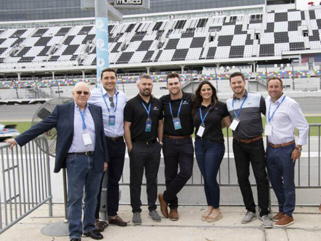 Impel team group photo at a NASCAR event.